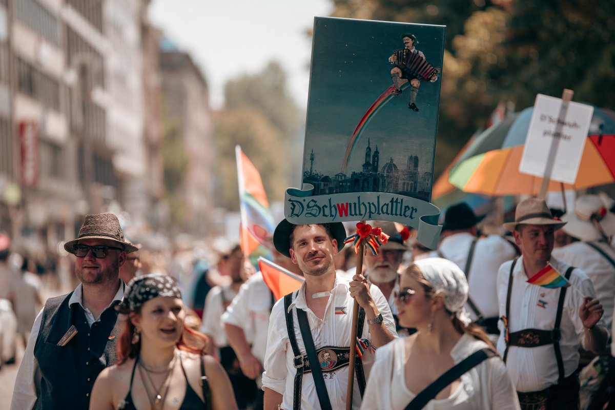 Demonstrierende tragen Plakate und Sonnenschirme durch die sonnige M?chner Innenstadt.