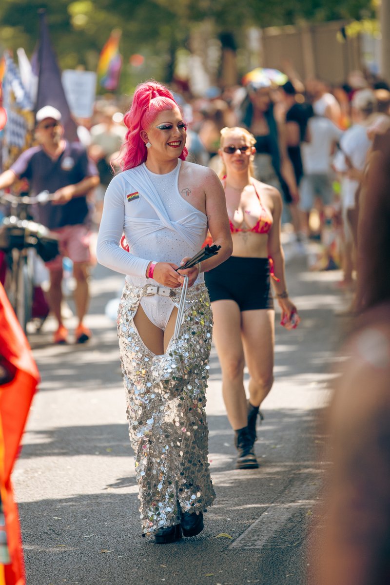 Teilnehmer in glitzerndem Outfit l?ft durch die Parade, im Hintergrund verfolgen Menschen den Zug.