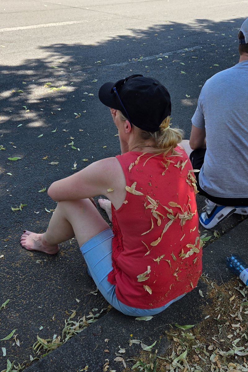 Teilnehmer sitzt am Stra?nrand im Schatten und ruht sich w?rend des hei?n CSD-Tages aus.