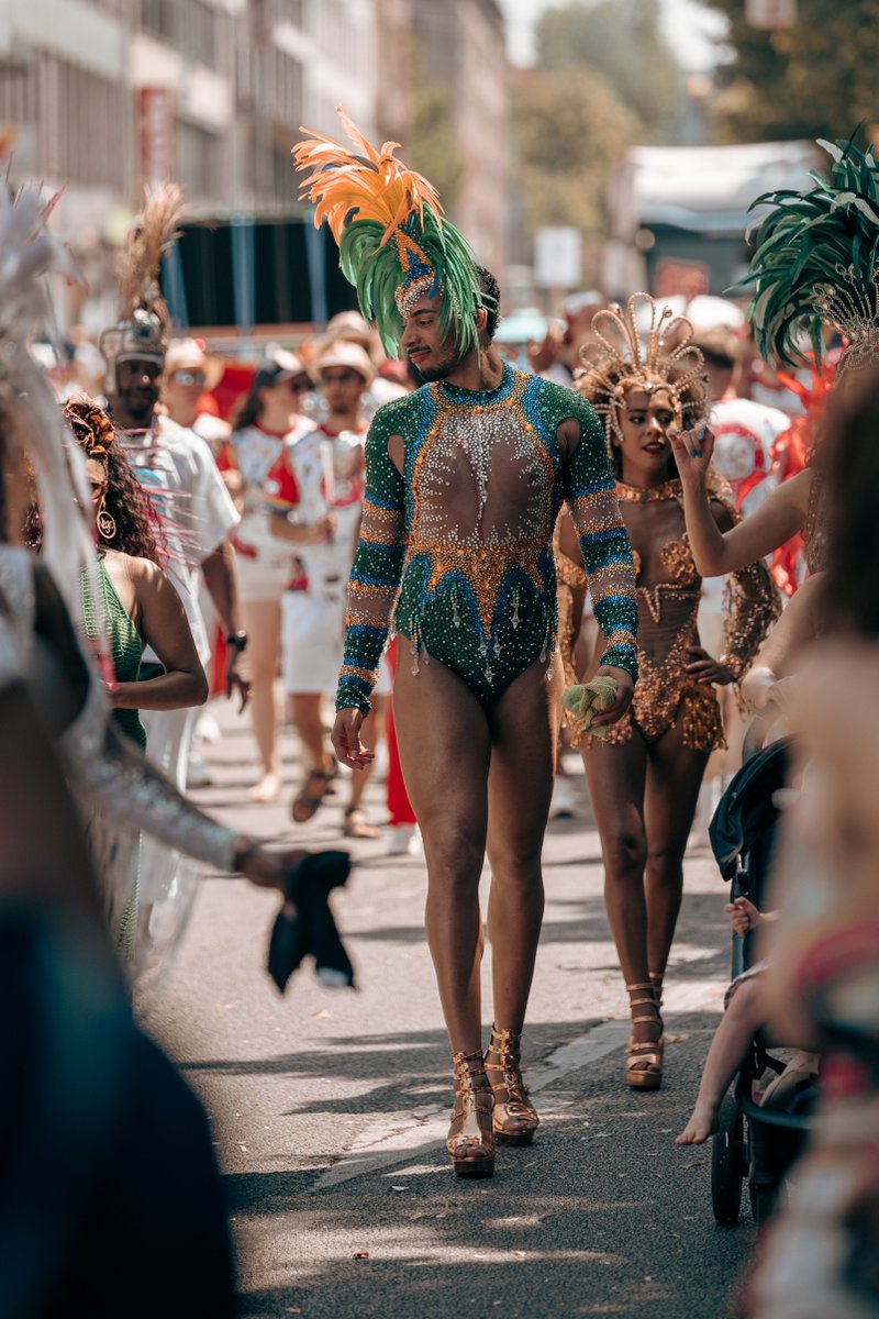 Person in gr?-glitzerndem Parade-Outfit l?ft selbstbewusst durch die M?chner Pride-Parade.