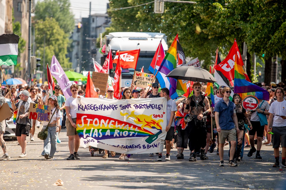 Gro? Demonstrationsgruppe mit Banner, Flaggen und Schildern kommt die Stra? entlang.