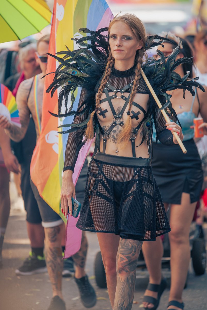 Teilnehmerin in schwarzem Netz-Outfit l?ft selbstbewusst vor Pride-Flaggen.