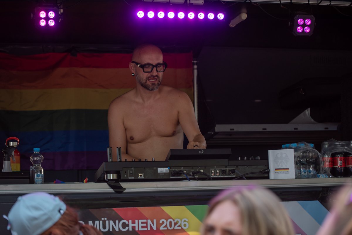 DJ steht auf einer B?ne mit violettem Licht beim CSD München 2026.
