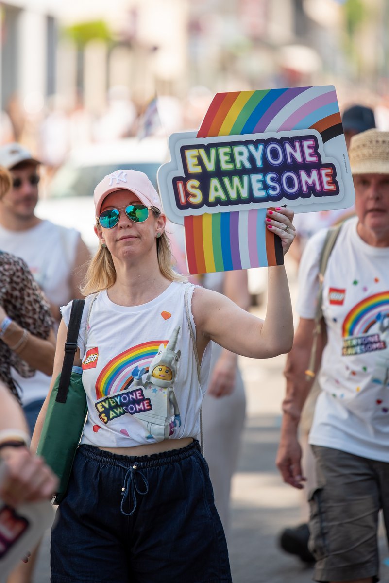 Teilnehmerin mit Sonnenbrille h?t ein ?Everyone is awesome?-Schild in der Menge hoch.