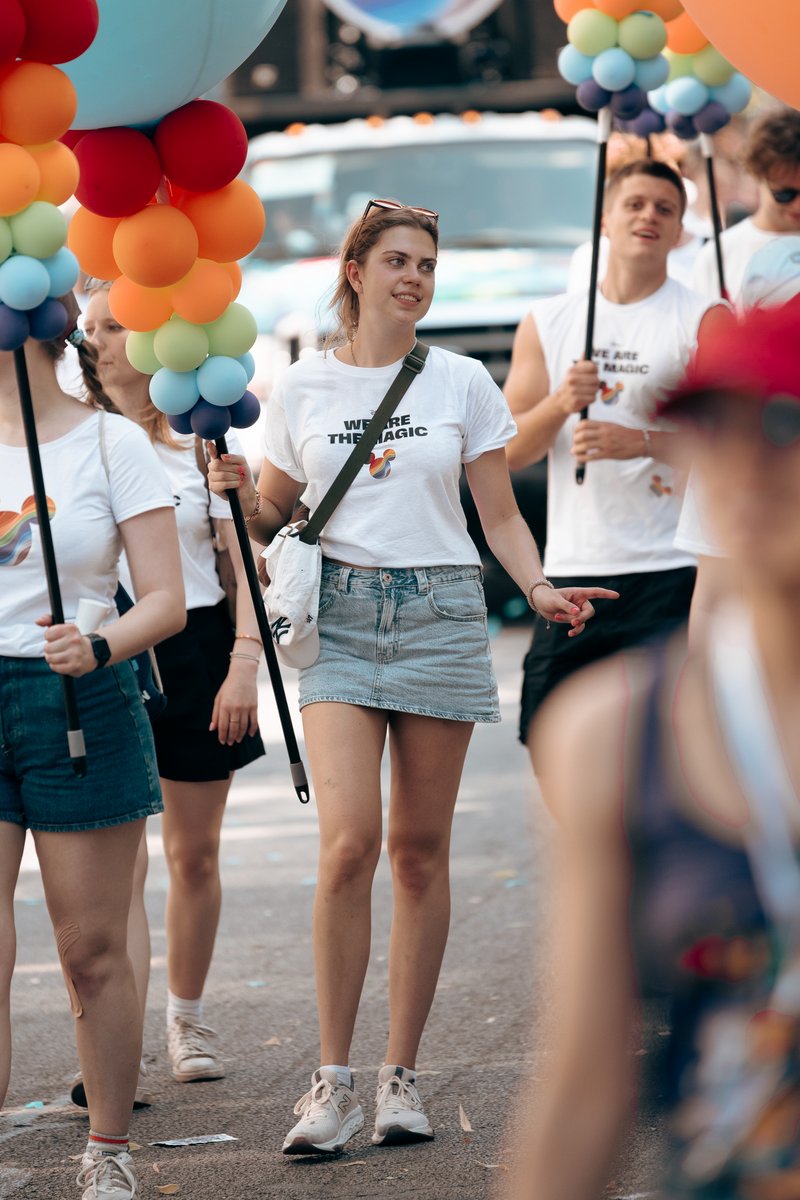 Zwei junge Teilnehmende laufen vor bunten Ballons durch die Parade.