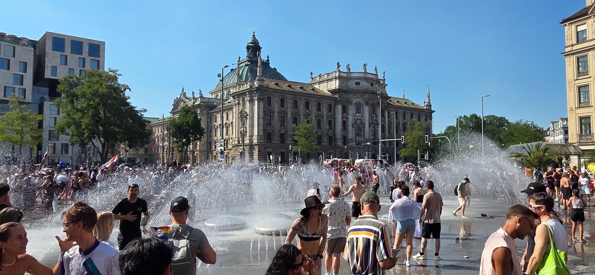 Breiter Blick auf den Brunnen am Karlsplatz mit vielen Menschen und Wasserfont?en.